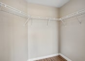 Thumbnail 17 of 27 - A white metal clothes rack in a room with beige walls.