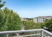 Thumbnail 19 of 27 - A balcony overlooks a residential area with houses and trees.