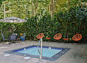 Thumbnail 14 of 27 - A pool surrounded by orange chairs and a green hedge.