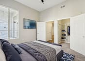 Thumbnail 8 of 28 - A bedroom with a bed, a window with blinds, a ceiling fan, and a closet with clothes.