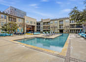Thumbnail 16 of 42 - A large swimming pool is surrounded by a concrete patio and lounge chairs.
