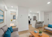 Thumbnail 9 of 32 - A living room with a grey couch and a wooden coffee table.