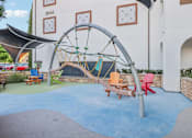 Thumbnail 30 of 38 - A playground with a swing set and a blue surface.