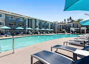 Thumbnail 14 of 24 - lounge chairs at sparkling pool at Pointe Luxe Apartment Homes, San Diego, CA, 92110