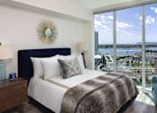 Thumbnail 29 of 33 - A bedroom with a large bed and a view of the city.