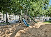Thumbnail 21 of 27 - A playground with a green slide and a brown ground.