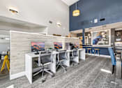 Thumbnail 23 of 31 - A modern office space with a white desk, blue chairs, and a yellow caution sign.