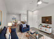 Thumbnail 7 of 28 - A living room with a blue couch and a television on a cabinet.