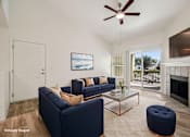 Thumbnail 6 of 27 - A living room with a blue couch and a fireplace.
