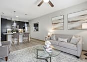 Thumbnail 42 of 42 - A modern living room with a grey couch and a glass coffee table.