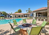 Thumbnail 21 of 28 - A poolside area with a fire pit and chairs.