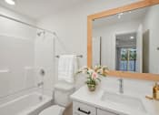 Thumbnail 14 of 32 - A white bathroom with a large mirror and a white toilet.