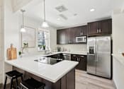 Thumbnail 1 of 27 - A modern kitchen with a white countertop and stainless steel appliances.