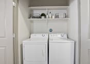 Thumbnail 29 of 42 - A white washing machine and dryer in a small laundry room.