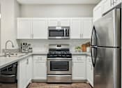 Thumbnail 1 of 28 - A modern kitchen with stainless steel appliances and white cabinets.