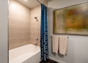 Thumbnail 23 of 23 - A bathroom with a white tub and blue shower curtain.