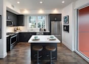 Thumbnail 16 of 33 - A modern kitchen with a large island and stools.