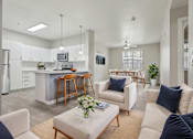 Thumbnail 8 of 28 - A modern living room with a kitchen in the background.