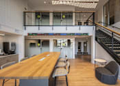 Thumbnail 21 of 28 - a communal table and chairs in a large room with stairs