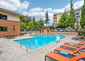 Thumbnail 11 of 31 - A large outdoor swimming pool surrounded by orange lounge chairs.
