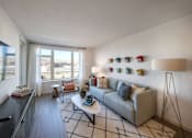 Thumbnail 9 of 28 - a living room with a couch and a table and a window