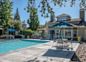 Thumbnail 19 of 32 - Swimming Pool Area With Shaded Table And Chairs at Atwood Apartments, Citrus Heights, CA