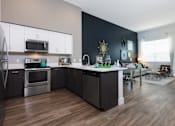 Thumbnail 2 of 24 - a kitchen with white cabinets and stainless steel appliances and a table with a chair in the background