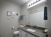 Thumbnail 16 of 20 - A bathroom with a toilet, sink, mirror, and wall decorations.