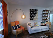 Thumbnail 17 of 20 - A living room with a white couch and a chair with orange cushions.