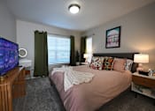 Thumbnail 15 of 20 - A bedroom with a bed, a television, and a window with blinds.
