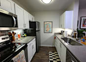Thumbnail 18 of 20 - A kitchen with black appliances and white cabinets.