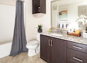 Thumbnail 9 of 21 - A bathroom with a white toilet, a sink, and a mirror.
