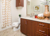 Thumbnail 7 of 21 - A bathroom with a toilet, sink, and a mirror.