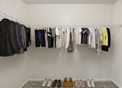 Thumbnail 5 of 16 - a closet with clothes hanging on a rack and shoes on the floor