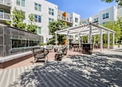 Thumbnail 21 of 40 - a patio with awnings and benches in front of an apartment building
