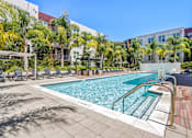 Thumbnail 17 of 40 - a swimming pool with chairs and a building in the background