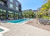 Thumbnail 18 of 40 - a swimming pool with lounge chairs in front of a building