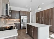 Thumbnail 17 of 20 - A modern kitchen with a white island and stainless steel appliances.