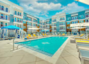 Thumbnail 5 of 29 - A swimming pool surrounded by sun loungers and umbrellas in front of a multi-story hotel.