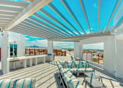 Thumbnail 26 of 29 - A patio with a white roof and striped cushions.