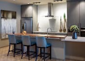 Thumbnail 15 of 21 - A modern kitchen with a bar area and chairs.
