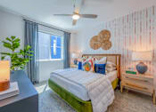 Thumbnail 7 of 24 - A bedroom with a bed, nightstand, and a plant.