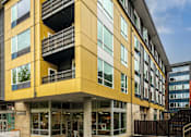 Thumbnail 2 of 25 - A yellow and black building with a balcony on the second floor.