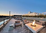 Thumbnail 22 of 30 - a rooftop lounge with a fire pit and tables