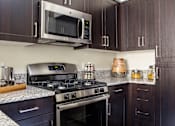Thumbnail 3 of 21 - A modern kitchen with dark wood cabinets and stainless steel appliances.
