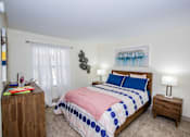 Thumbnail 7 of 20 - A bedroom with a bed, nightstand, and a painting on the wall.