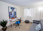Thumbnail 6 of 20 - A room with a desk, chair, and a painting of a shirt on the wall.