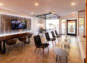 Thumbnail 19 of 27 - a lounge room with tables and chairs and a tv on the wall