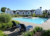 Thumbnail 28 of 32 - A pool surrounded by chairs and a grassy area.