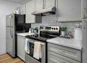 Thumbnail 3 of 27 - A modern kitchen with a black refrigerator, stainless steel oven, and white countertops.